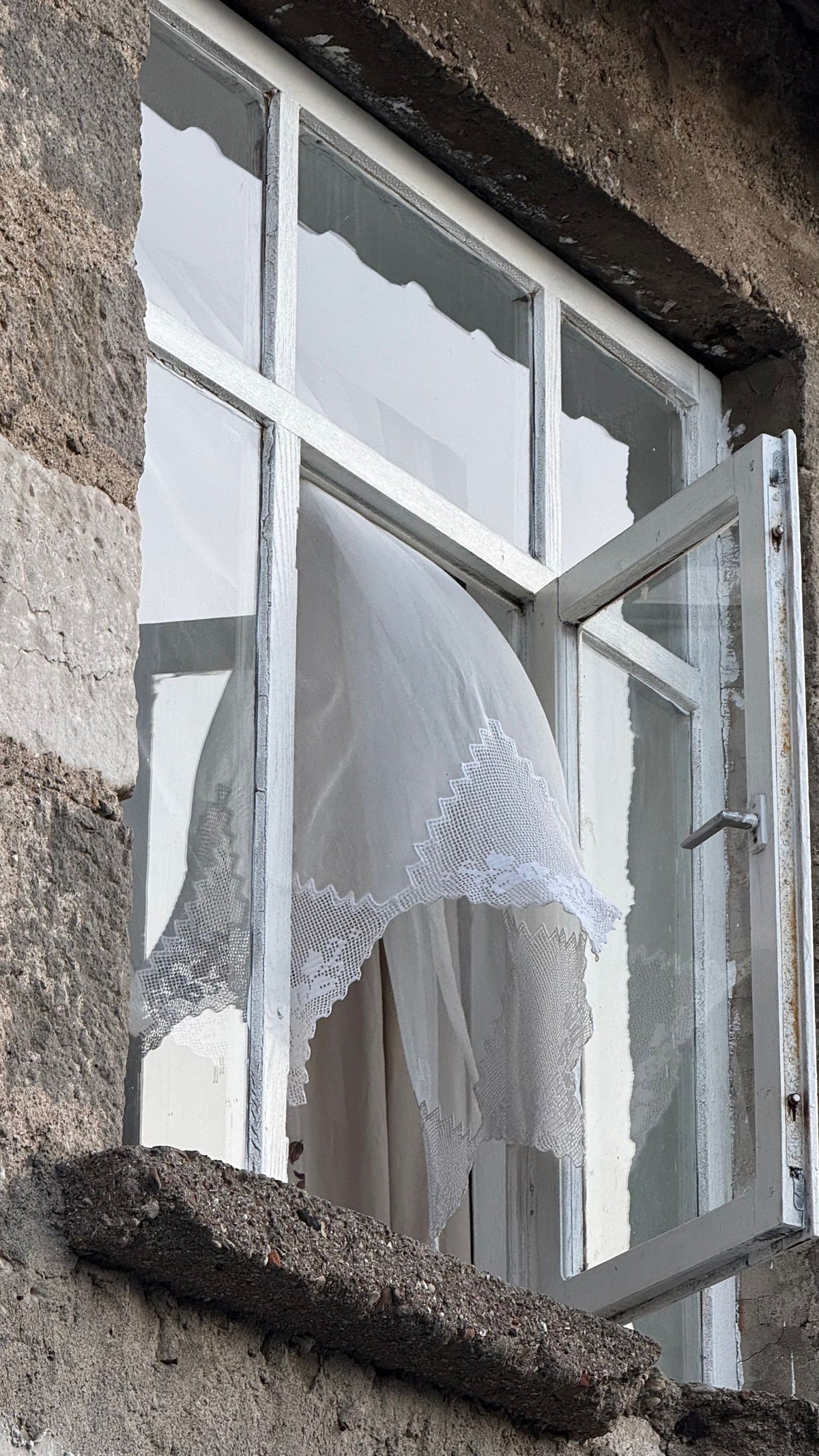Offenes Fenster mit wehender Gardine