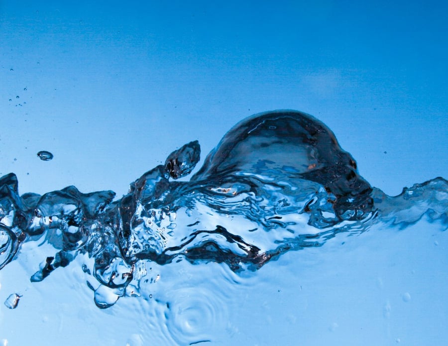 Wasserspritzer und Blasen vor blauem Hintergrund
